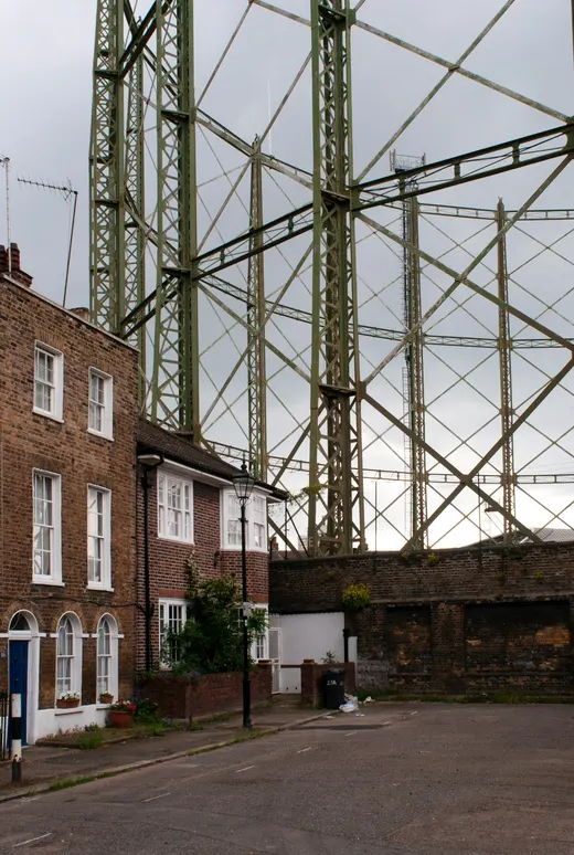Backsteinhäuser vor einem Gasometer